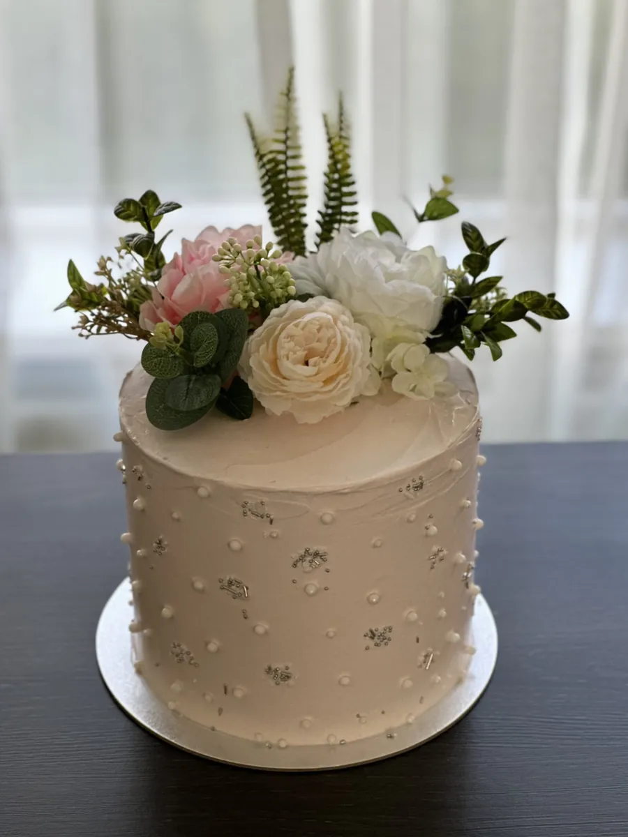 Witte taart met suikerparels en verse bloemen