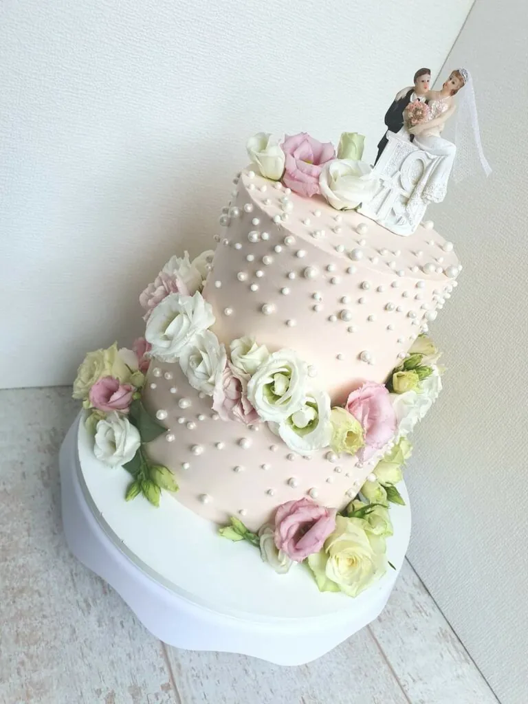 Roze bruidstaart met bloemen en suikerparels